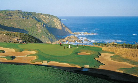 Golfers on the green at the Signature hole at Pezula Golf Club perched on the cliffs.
