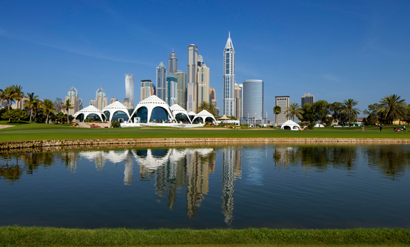 The clubhouse at the Emirates course is reflected in the lake with sky scrapers of Dubai City in the distance.