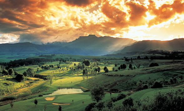 dramatic orange clouds and mist over the golf course with the Drakensberg Mountains in the distance.