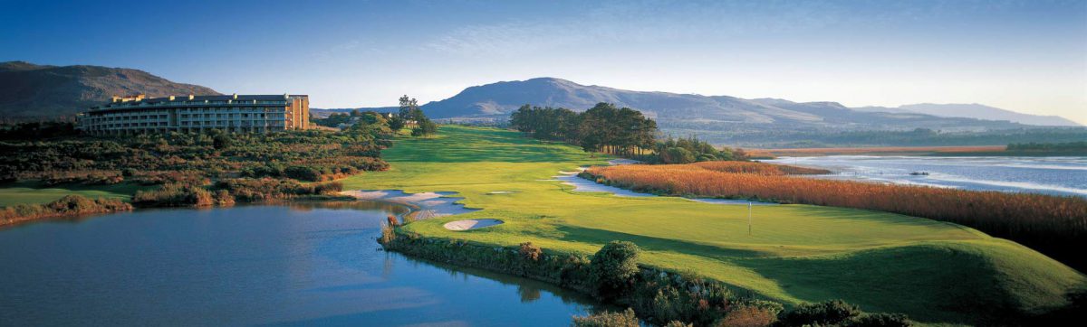 Golf fairway and green surrounded by lagoon water wit hotel on the ridge