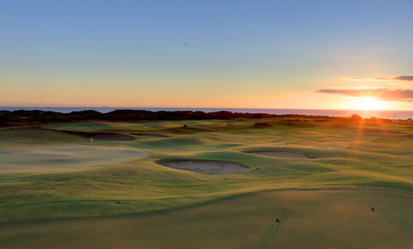 Sunsetting over the sea with long shadows on the golf course fairways.