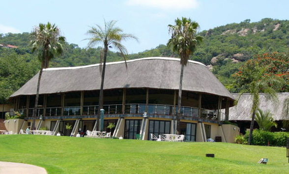 Thatched Clubhouse at Nelspruit Golf Course with palm trees in the foreground.