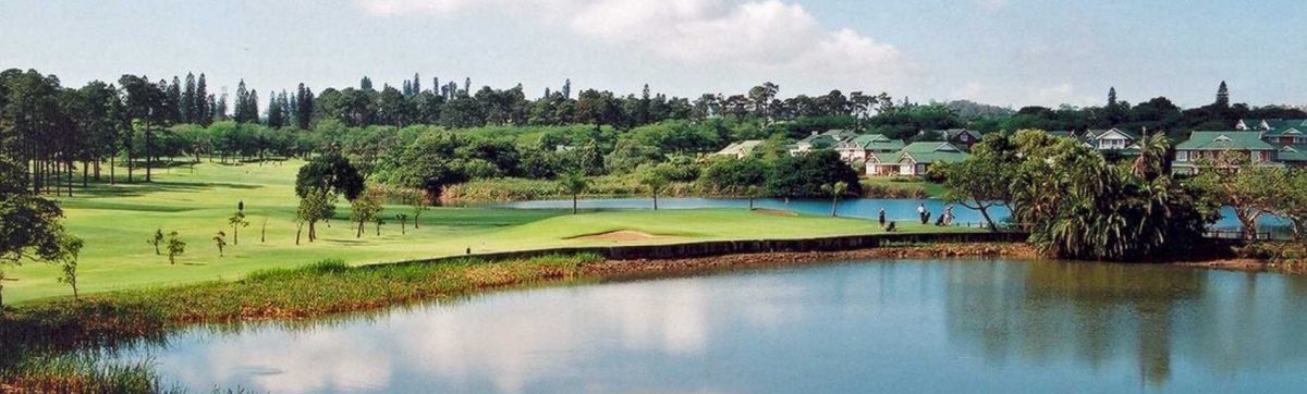 Golfers playing on the green fairways, surrounded by lakes and trees.