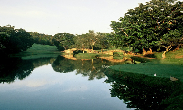 stone bridges across the lake are reflected in the evening sunlight at Selborne.