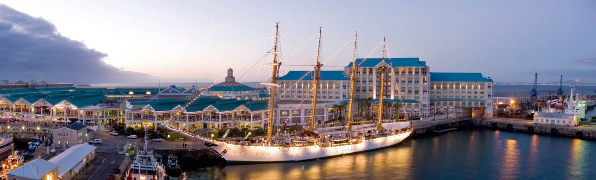 White hulled Tall Ship moored in the harbour at Cape Town with building and lights.