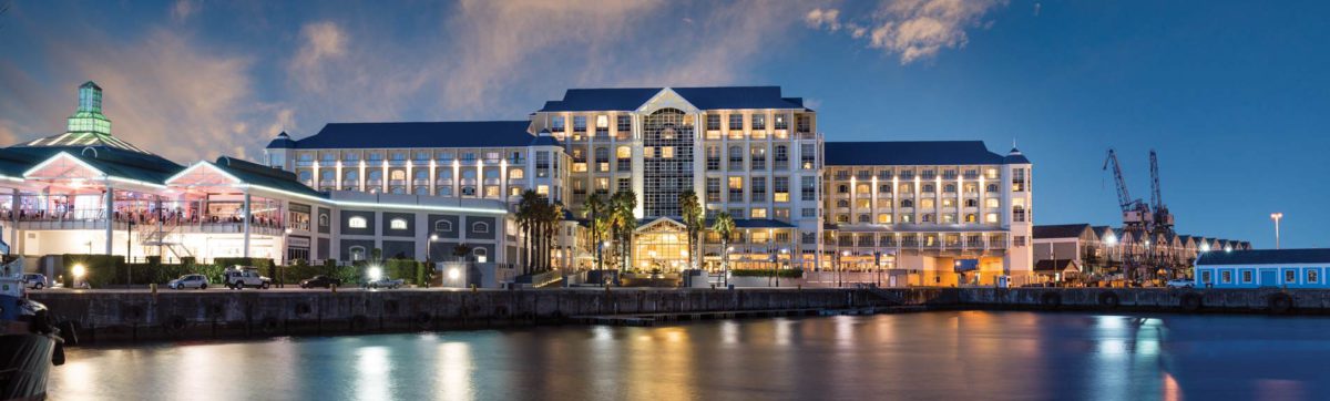 Sun set in the harbour with hotel lit up and reflections in the water.