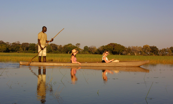 couple enjoy a canoe safari as the sun begins to set over the water.