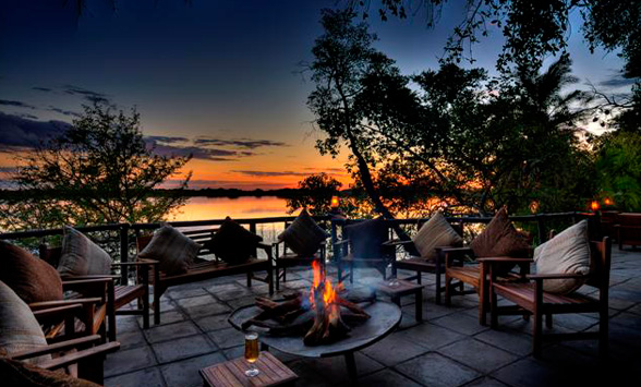 fire roaring on the deck overlooking the lagoon with a red and orange sunset in the sky.