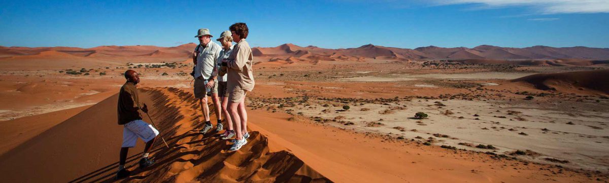 Tourists on the top of he red dunes in Sossusveli, Namibia.