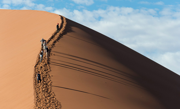 Tourists climbing the red dunes at Sossusvlei in Namibia.