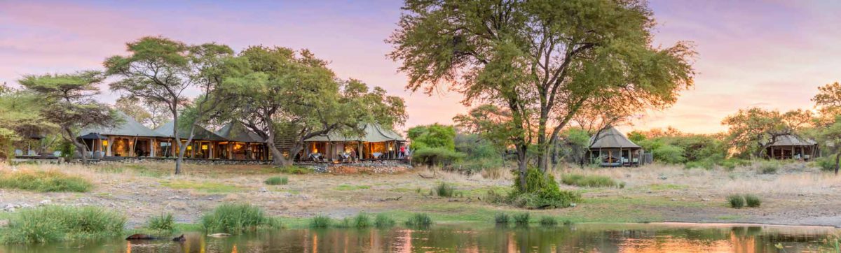 view across the waterhole to the Onguma tented camp at sunset.