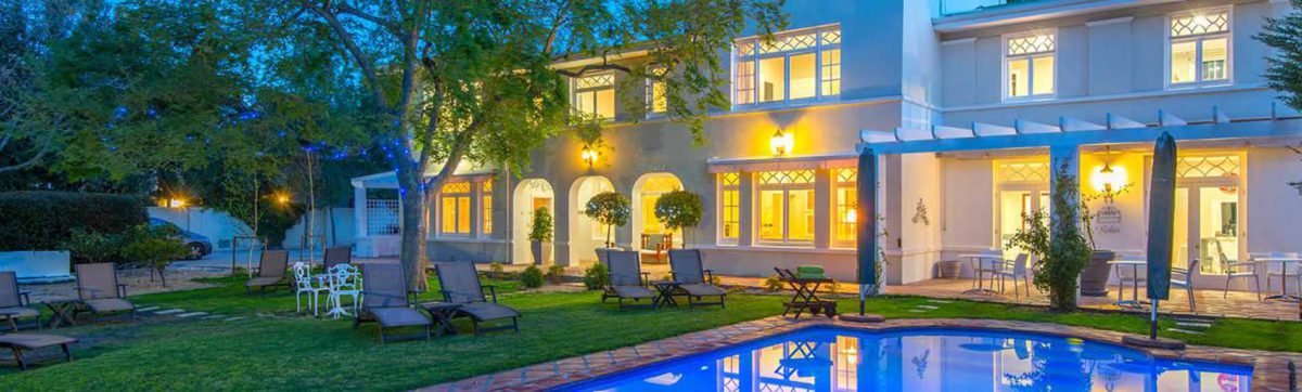 reflections in the pool of the Summerwood Guest house building lit up at night.