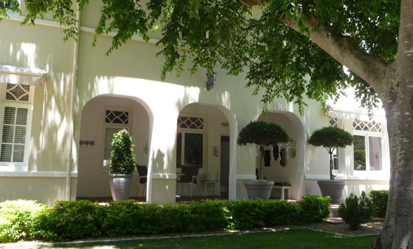 Front entrance of Summerwood, with shady trees and planters outside in the garden.