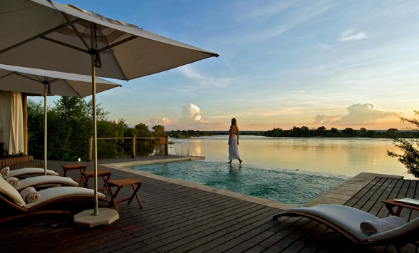 lady enjoying a sunset stroll by the pool at Sussi and Chuma as sun sets over the Zambezi River