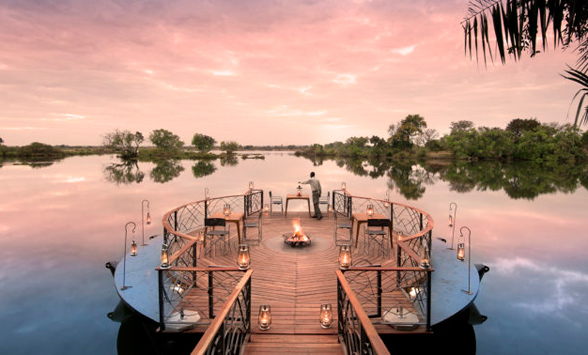 sun sets over the zambezi river as the fire pit is lit at Thorntree River Lodge.