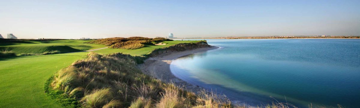 Iconic Alder Headquarters building in the distance behind the fairways of the Yas Links Golf Club.