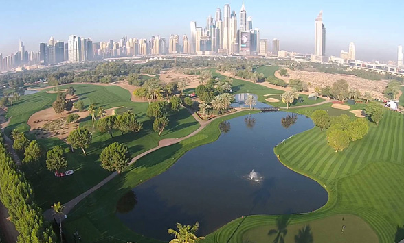 Aerial view of the Emirates Golf Club with sky scrappers of Dubai City in the distance.