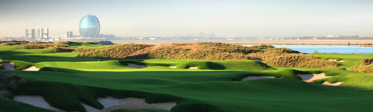 long shadows over the Yas Links golf course with eh Alder Head quarters in the back ground.