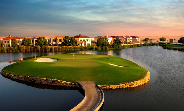 sun setting over the water surrounding the island green at Jumeirah Earth golf course.