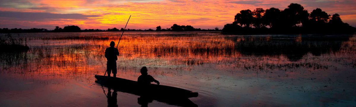 Mokoro canoe silhouetted against the Orange and red sunset in the Okovango.