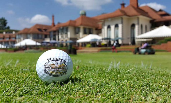 close up of golf ball with Windsor Golf Hotel logo and club house in the back ground.