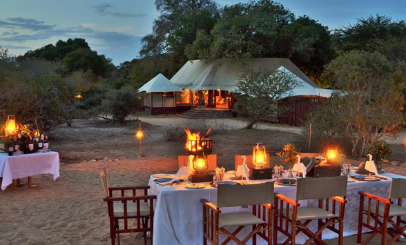 Dining tables laid up outside, around a boma fire