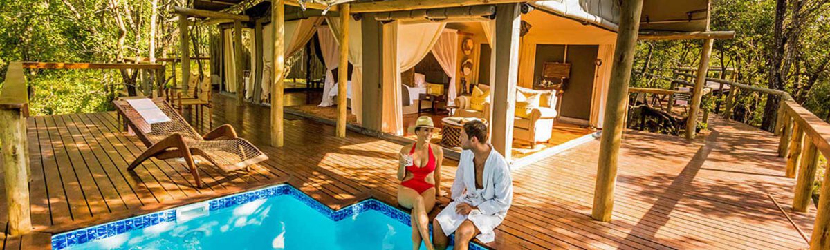 couple sitting on the deck with their feet in the plunge pool and enjoying a glass of wine.